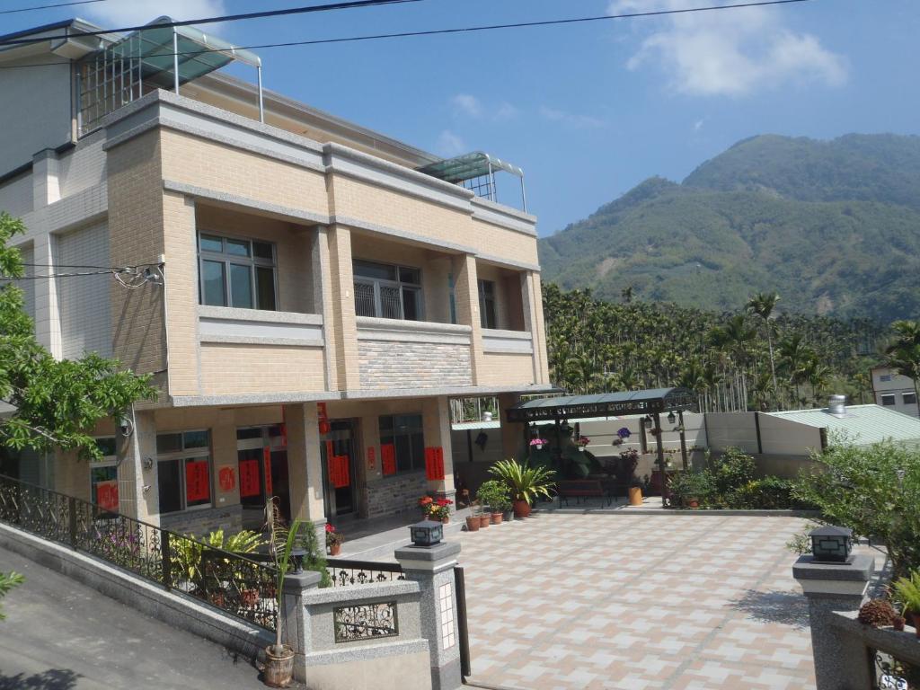 un bâtiment avec des montagnes en arrière-plan dans l'établissement De Ren Tea Gardens, à Meishan