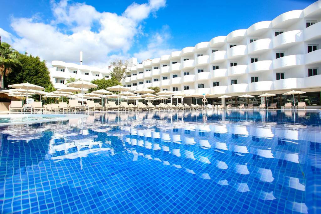 a large swimming pool with umbrellas and a hotel at Sentido Fido Tucan - Beach Hotel in Cala d´Or