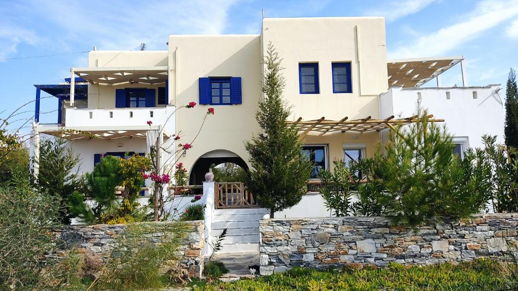 a white house with blue windows and a stone wall at Actis Studios in Stelida