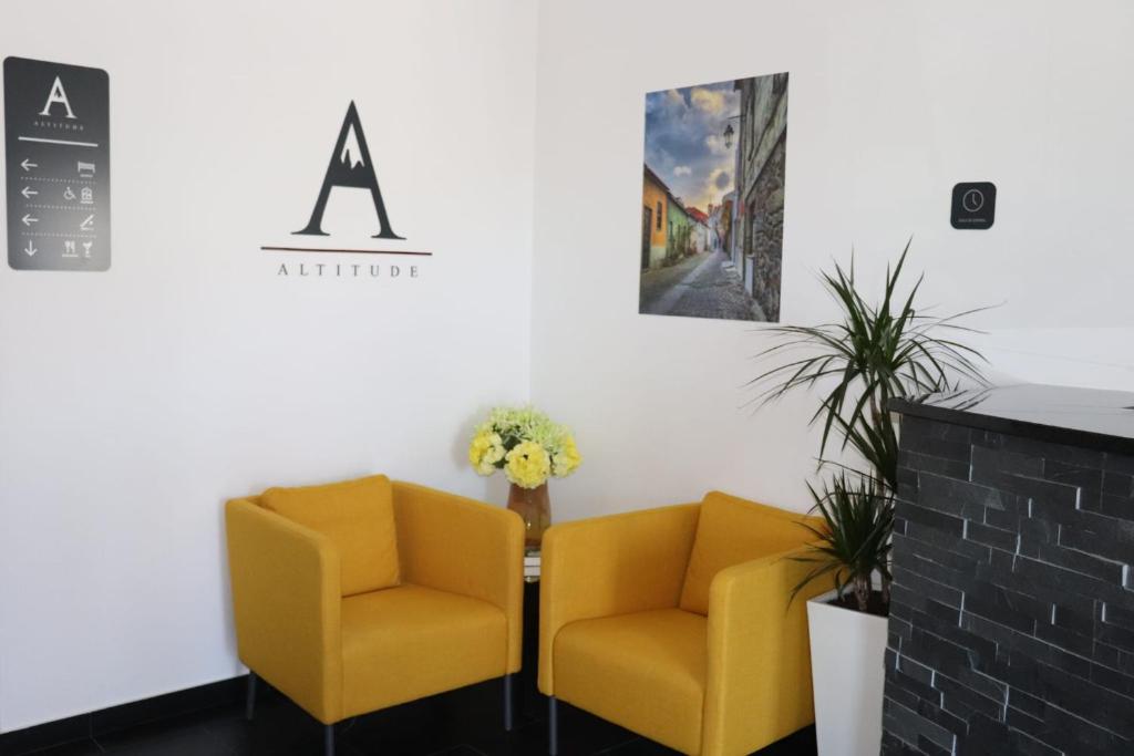 two yellow chairs sitting next to a table in a waiting room at Altitude Alojamento e Restauração in Belmonte