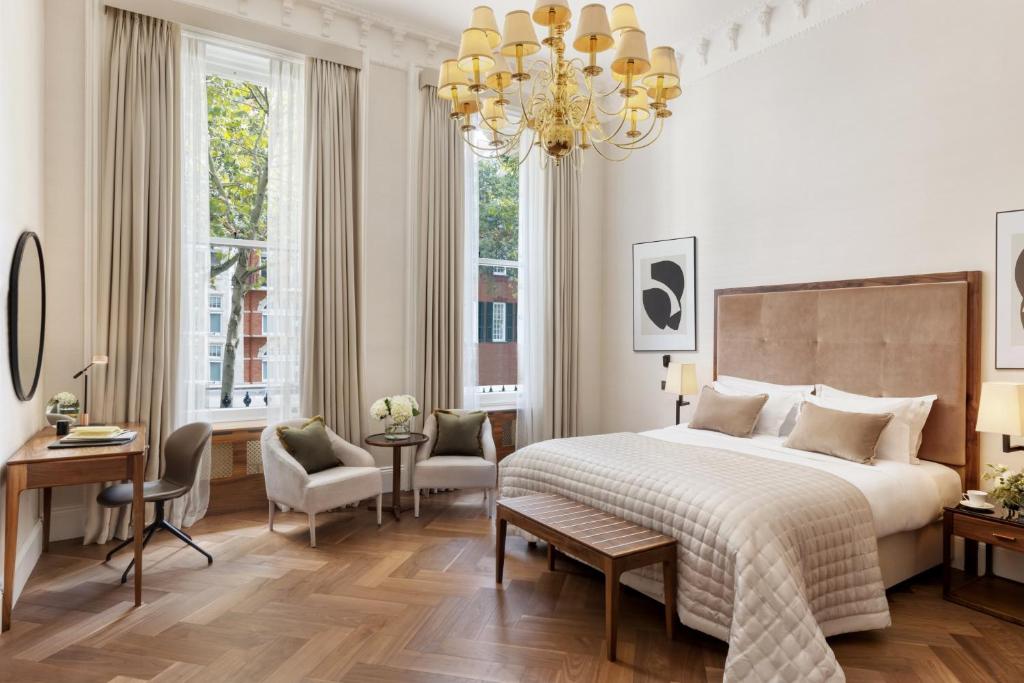 a bedroom with a large bed and a chandelier at The Queens Gate Hotel in London