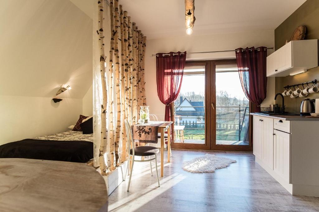 a bedroom with a bed and a table and a kitchen at Apartamenty Magiczny Kącik in Poronin