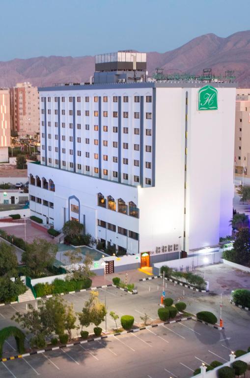 un grande edificio bianco con un cartello verde di Hotel Muscat Holiday a Mascate