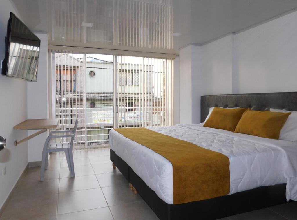 a bedroom with a bed and a desk and a window at Hotel Monarka-Edificio in Popayan