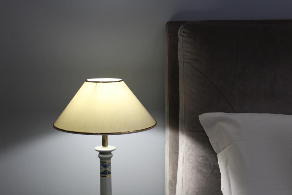 a lamp in a bedroom next to a bed at Homescape Frascati in Frascati