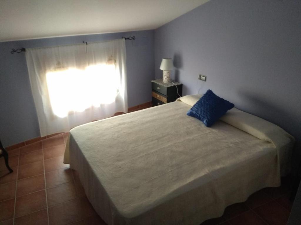 a bedroom with a bed with a blue pillow and a window at Casa Costeta in Cinctorres