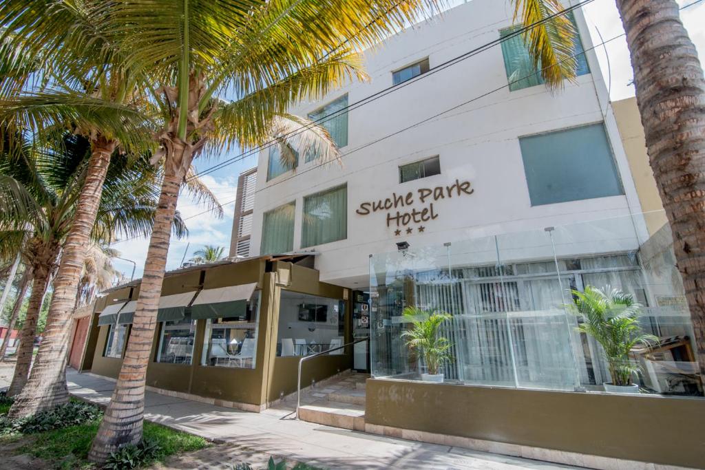 a building with palm trees in front of it at Suche Park Hotel in Piura