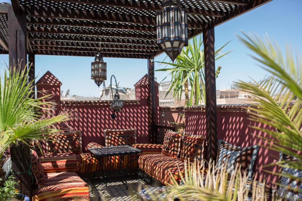 eine Terrasse mit Stühlen und einer Pergola in der Unterkunft Riad Tamarrakecht in Marrakesch