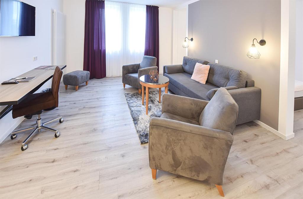 a living room with a couch and a desk at PRIMA Inn HOTEL & HOF NEURUPPIN - digitales & rezeptionsloses Motel in Neuruppin