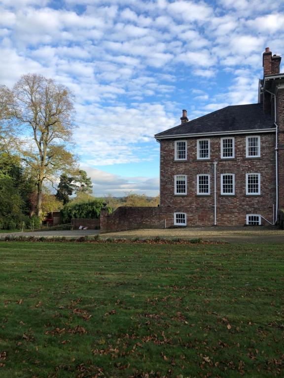 un grand bâtiment en briques avec une pelouse devant lui dans l'établissement Hall Cottage, Wighill near York and Leeds, à Tadcaster