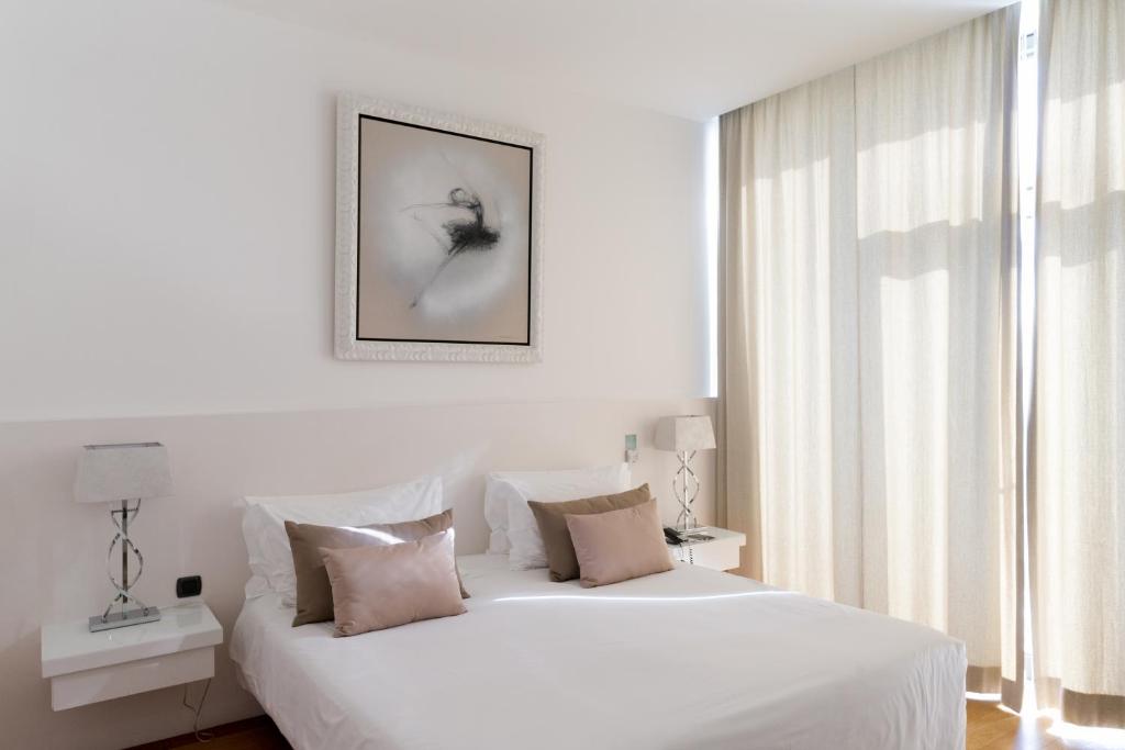 a bedroom with a white bed with a picture on the wall at Farol Hotel in Cascais
