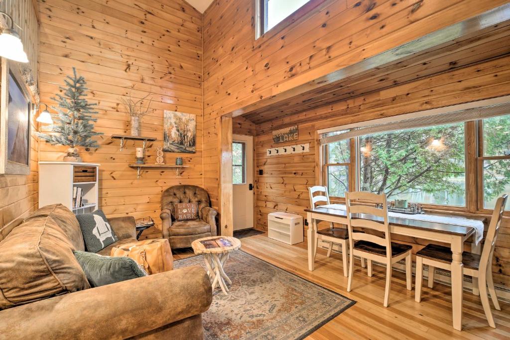 ein Wohnzimmer mit einem Sofa und einem Tisch in der Unterkunft Pet-Friendly Adirondack Cabin with On-Site Lake in Saranac Lake