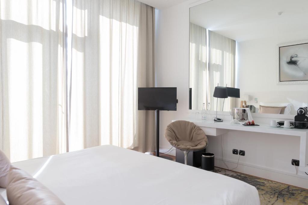 a bedroom with a white bed and a mirror at Farol Hotel in Cascais