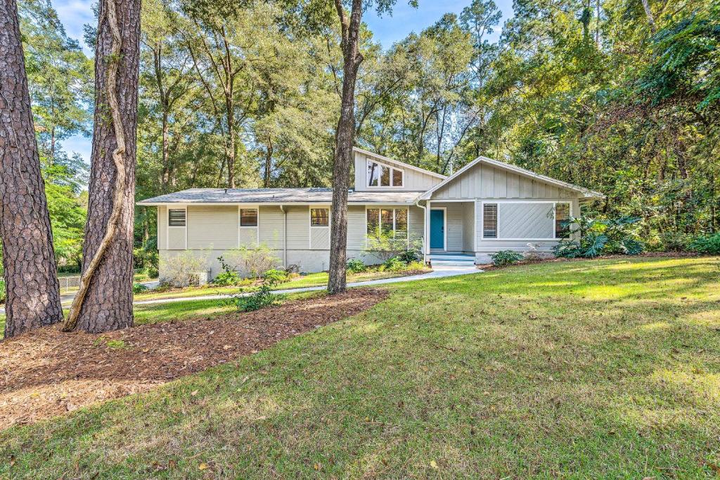 a white house with trees in front of a yard at Remodeled Family Home with Patio - Walk to UF! in Gainesville
