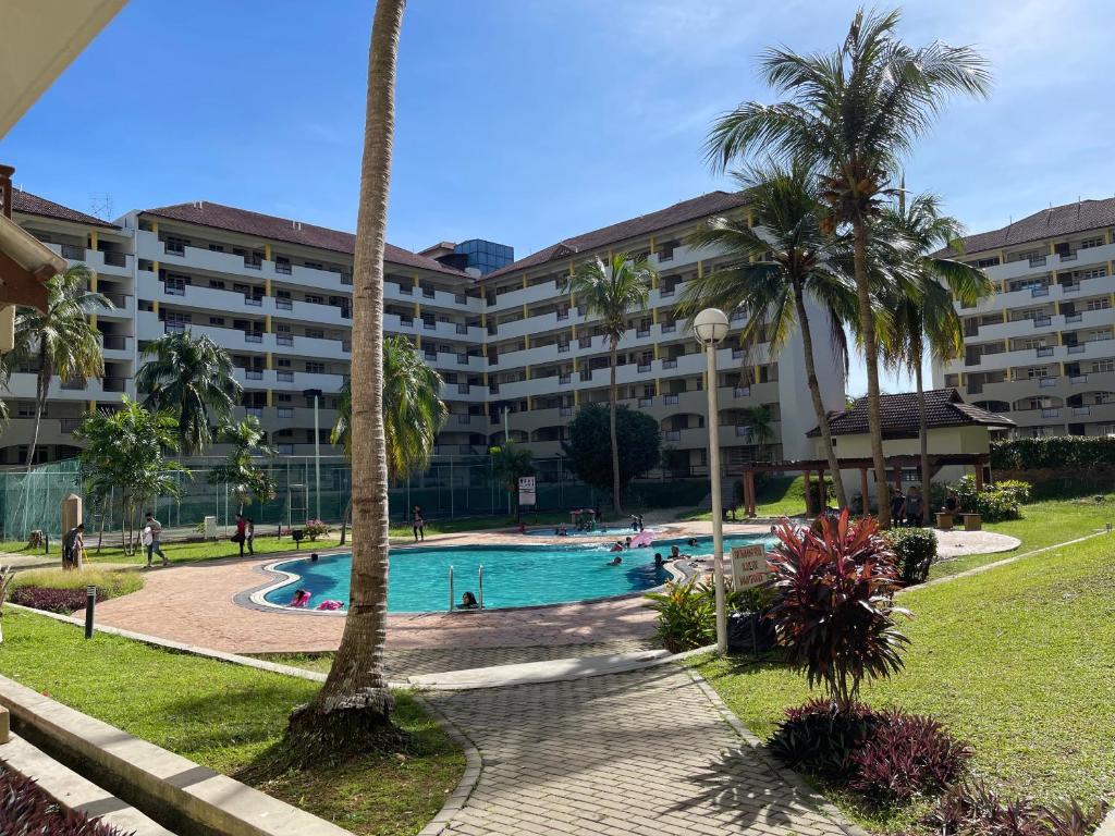 un complexe avec piscine et palmiers dans l'établissement SEA LA VIE BATIK @ LAGUNA RESORT, à Port Dickson