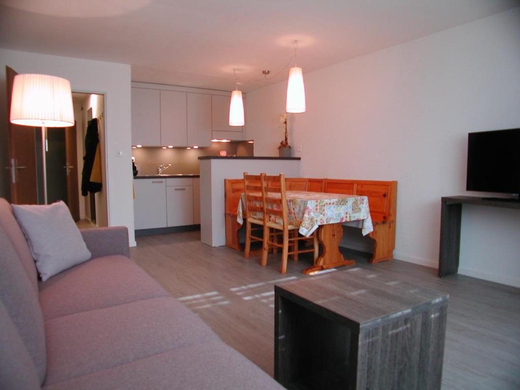 ein Wohnzimmer mit einem Sofa und einem Tisch sowie eine Küche in der Unterkunft Brunegghorn 4 in Grächen