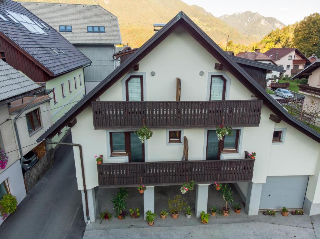 a white house with a balcony with flowers at Rooms Cvitar - Center in Kranjska Gora