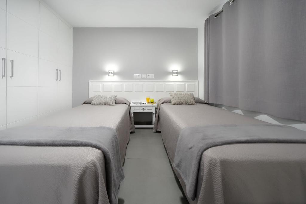 een kamer met 2 bedden en een fornuis bij Apartamentos Los Papagayos in San Agustin