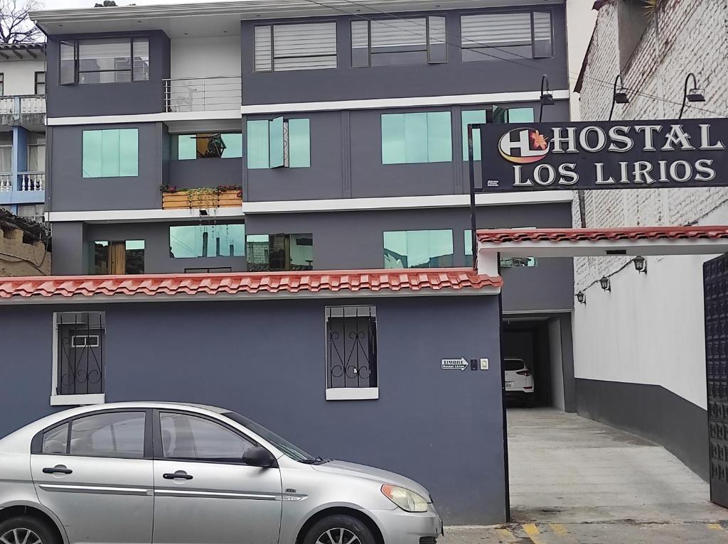 un coche plateado estacionado frente a un edificio azul en Hostal Los Lirios, en Loja