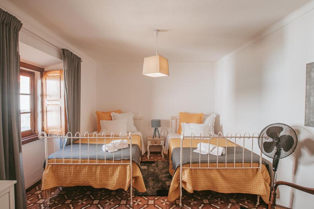 a bedroom with two beds and a lamp at Casinha do Roxo in Ervidel