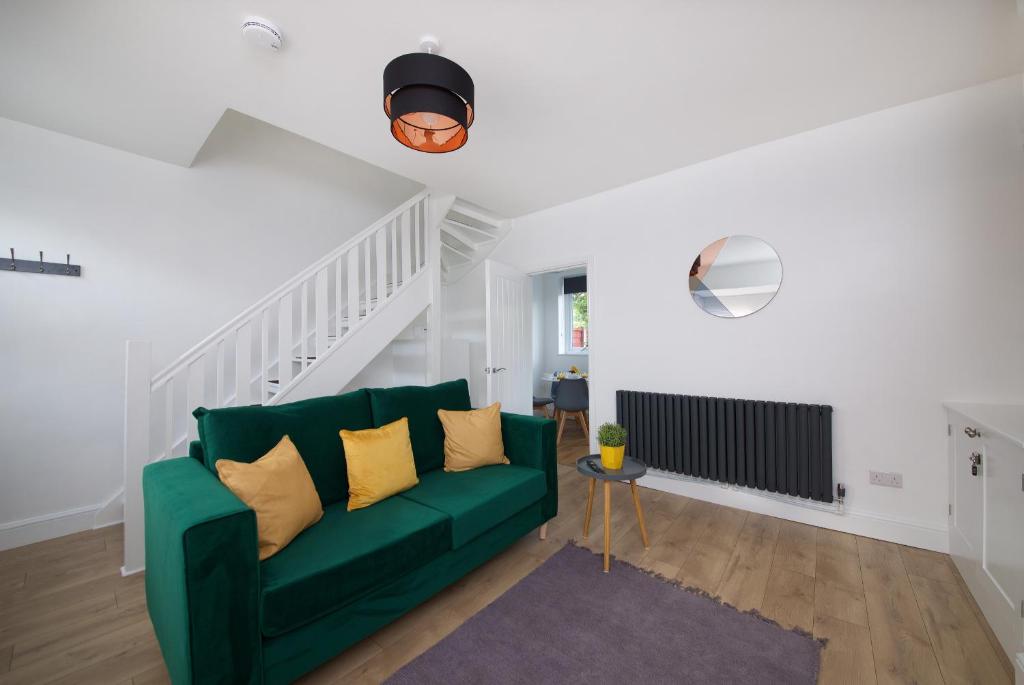 sala de estar con sofá verde y escaleras en Air Host and Stay - Thomson House - Sleeps 4 2 mins walk from Stockport train station and town centre en Stockport