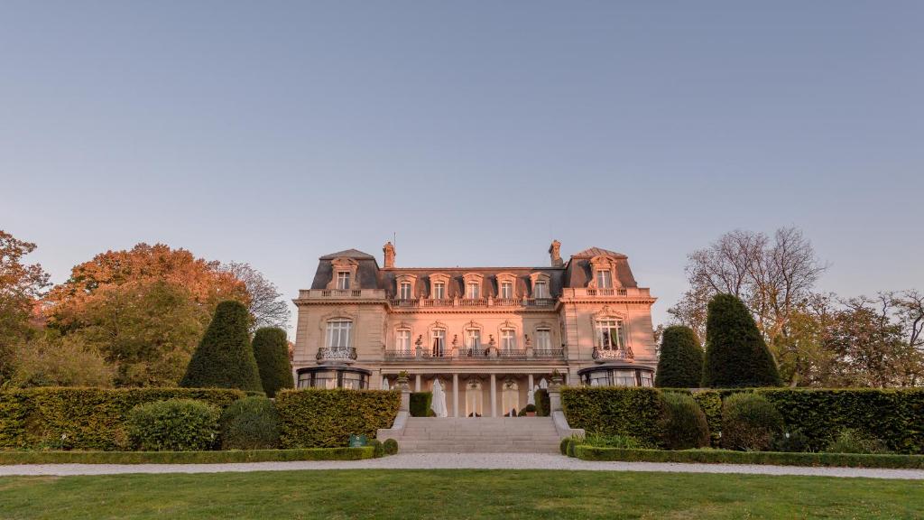 ein altes Herrenhaus mit Büschen und Bäumen davor in der Unterkunft Domaine les Crayères in Reims