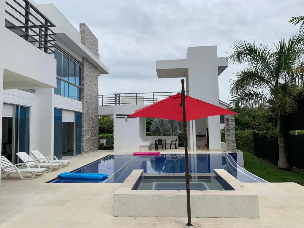 a red umbrella in front of a house with a swimming pool at Hermosa Villa de Descanso in Carmen de Apicalá