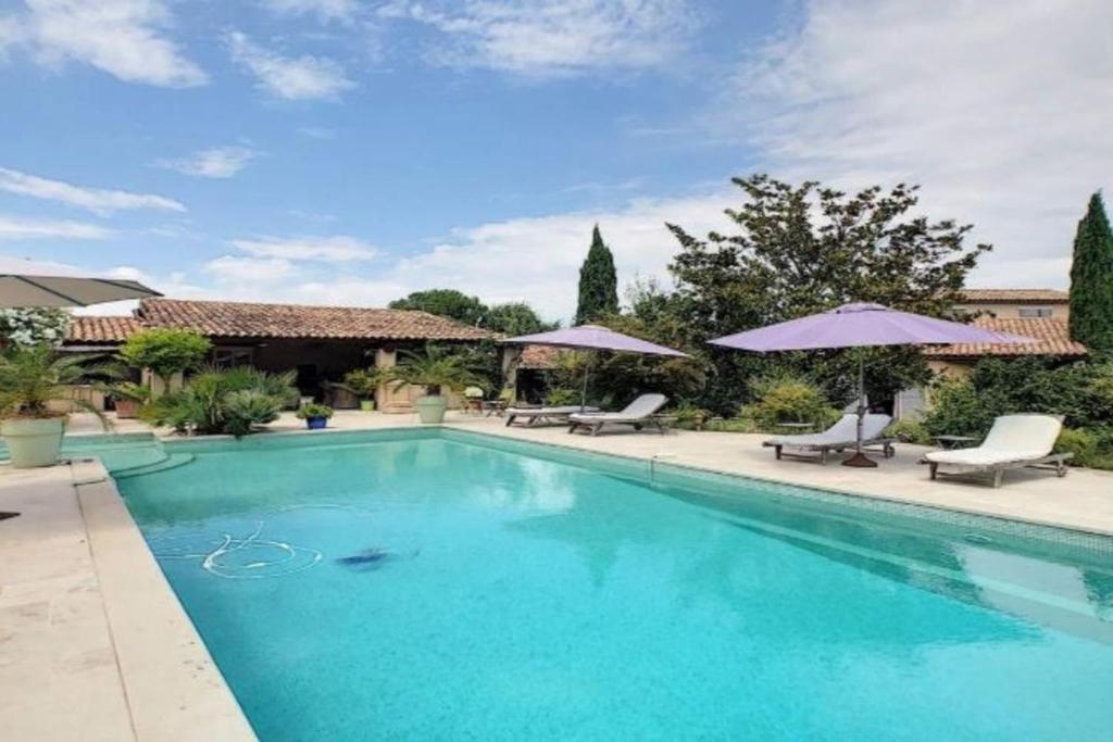 einen Pool mit Stühlen und Sonnenschirmen in der Unterkunft Gite Studio indépendant au cœur du Luberon in Maubec