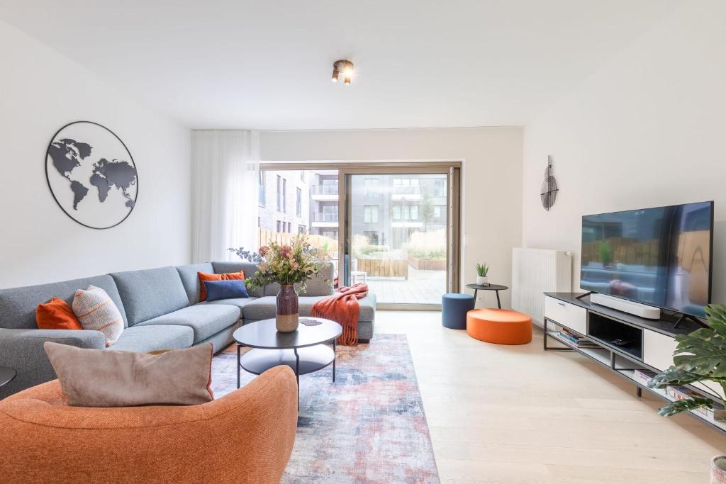 uma sala de estar com um sofá e uma televisão em Brand new holiday home with high-end finishing and private parking space, at a stone's throw from the beach em Ostend