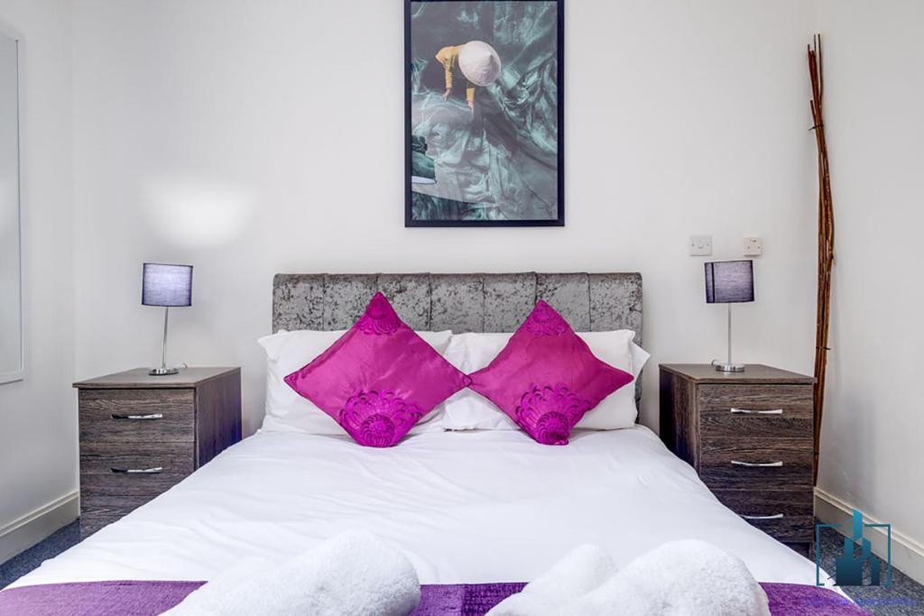 a bedroom with a white bed with pink pillows at City View Apartments in Birmingham