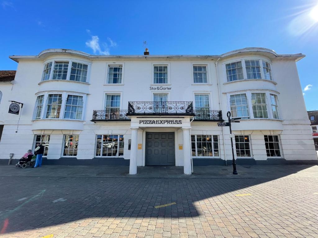 um edifício branco com uma varanda em cima em The Star and Garter Hotel em Andover