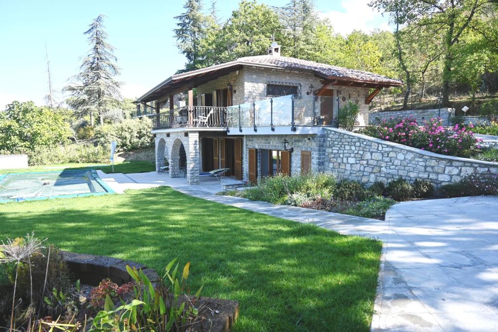 uma grande casa de pedra com uma varanda e um quintal em Villa Maria em San Feliciano