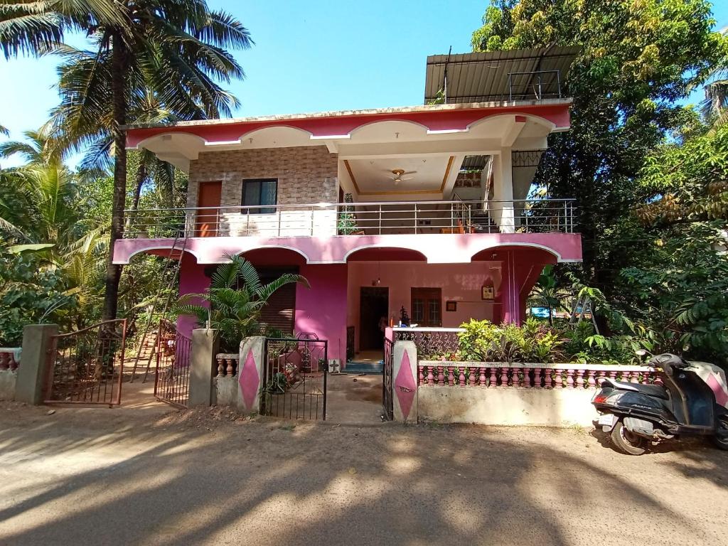 a pink house with a scooter parked in front of it at Jerone's Home Stay in Majorda