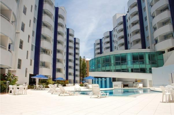 a courtyard with chairs and a pool in front of buildings at Águas da Serra Apart Hotel in Rio Quente