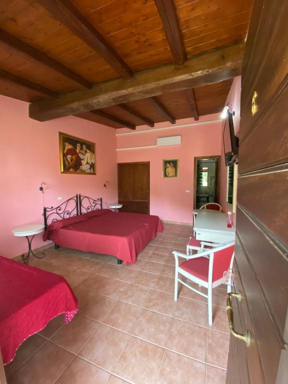 una camera da letto con pareti rosa, un letto e un tavolo di Agriturismo Montefosco a Sutri