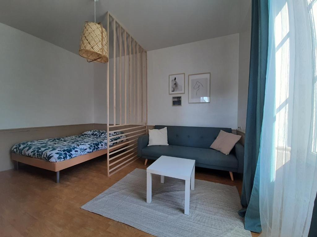 a living room with a blue couch and a bed at Gîte du Gavilu, appartement indépendant en cœur de ville in Mortagne-au-Perche