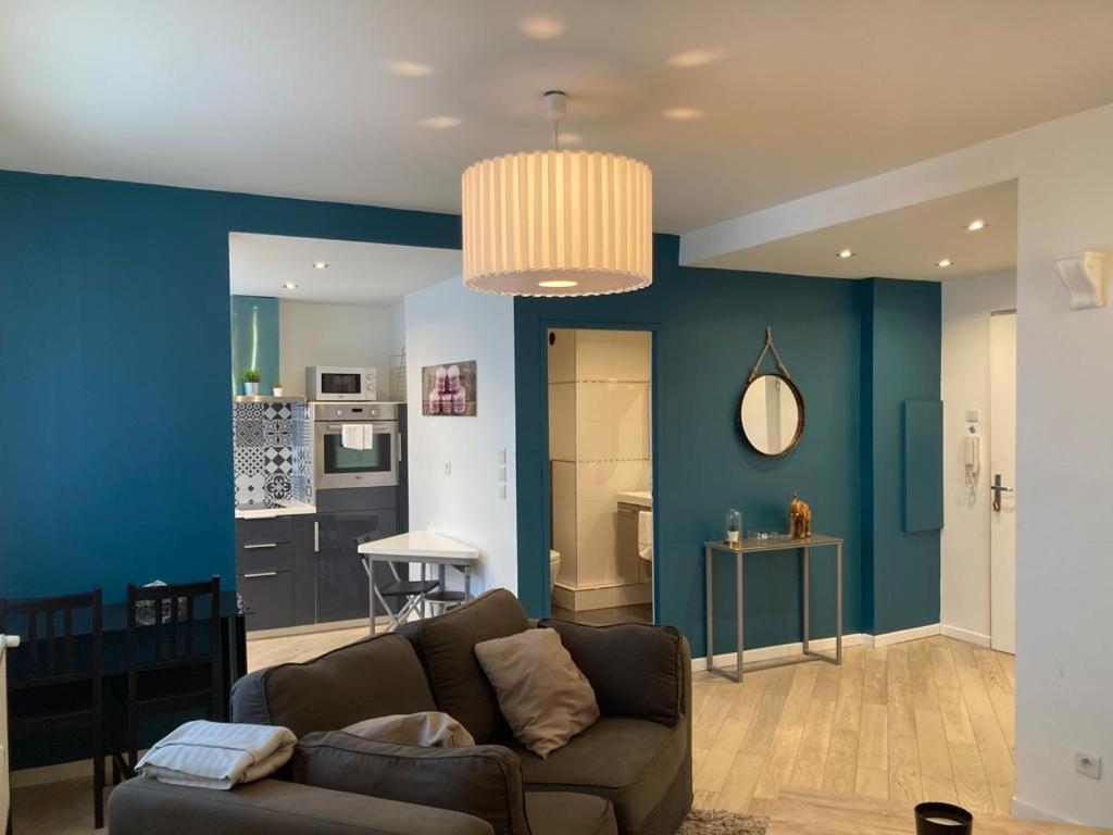 un salon avec un canapé et un mur bleu dans l'établissement Appartement 2P Strasbourg centre - Homme de fer, à Strasbourg
