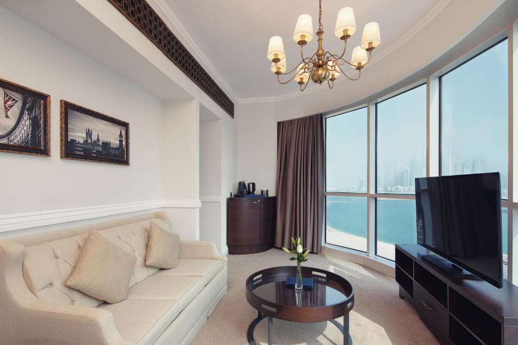 a living room with a white couch and a television at Dukes The Palm Dubai Hotel in Dubai