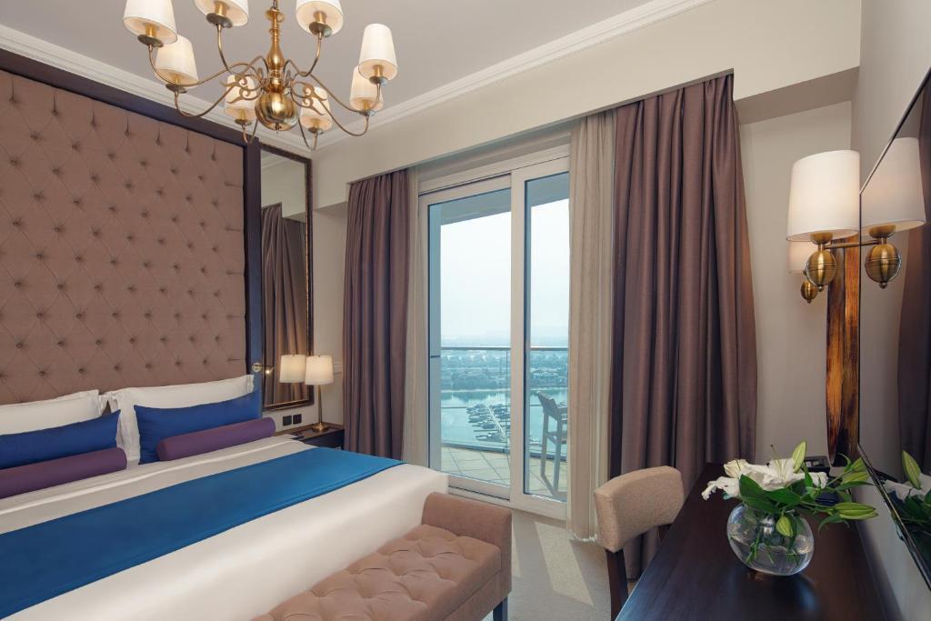 a bedroom with a large bed and a large window at Dukes The Palm Dubai Hotel in Dubai