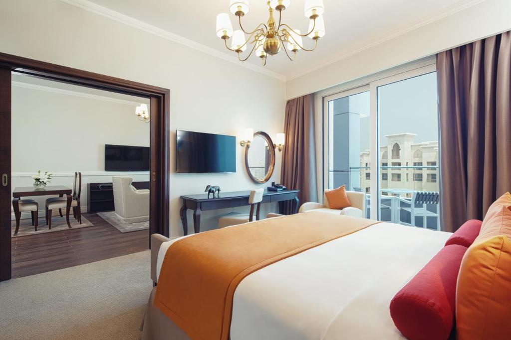 a hotel room with a large bed and a desk at Dukes The Palm Dubai Hotel in Dubai
