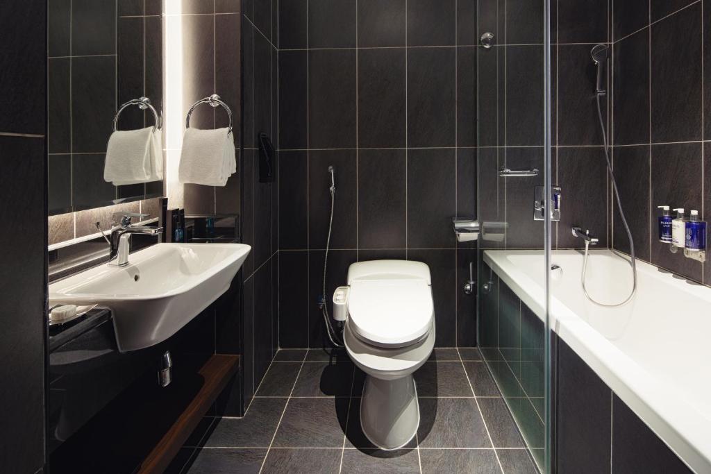 a bathroom with a toilet and a sink at Dukes The Palm Dubai Hotel in Dubai