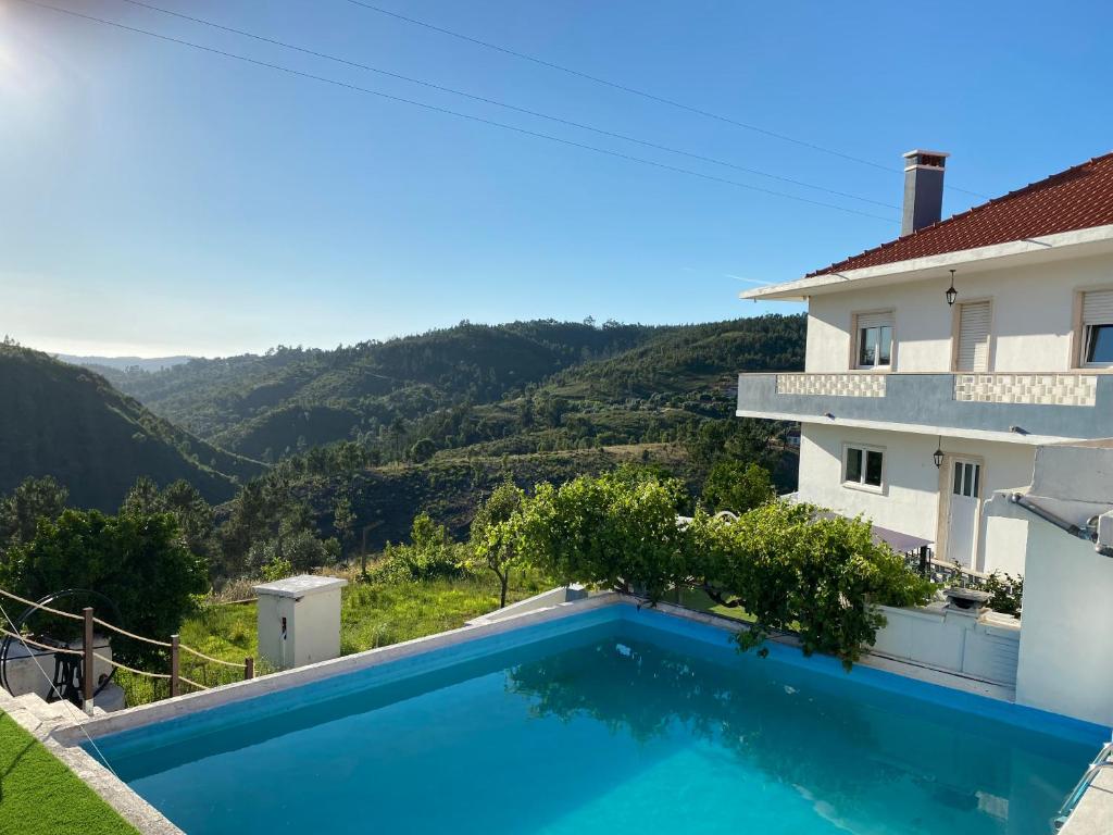 a swimming pool in front of a house with a mountain at Quinta Janelas do Vale in Abrantes