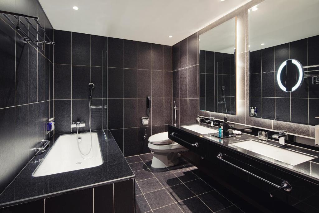 a bathroom with two sinks and a tub and a toilet at Dukes The Palm Dubai Hotel in Dubai
