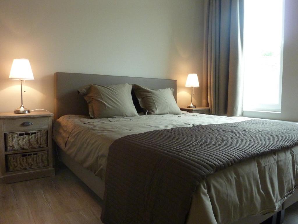 a bedroom with a bed with two lamps and a window at Aimée in Ypres