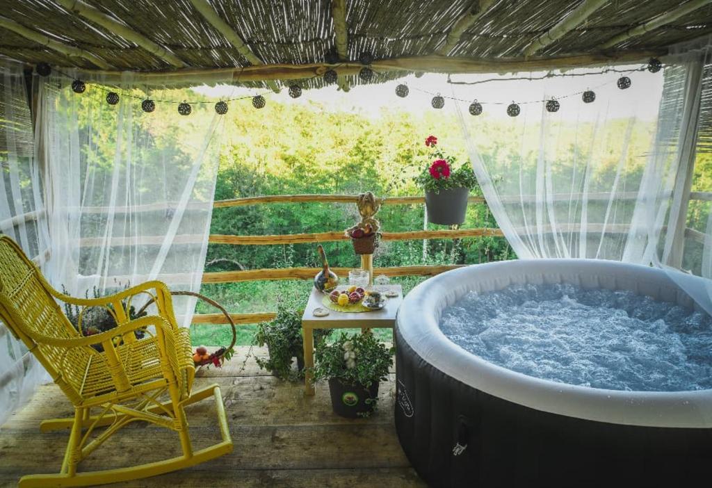 eine Badewanne auf einer Terrasse mit einem Tisch und einem Stuhl in der Unterkunft Kuća za odmor Vilin vrt Vrnjacka Banja Otroci in Vrnjačka Banja