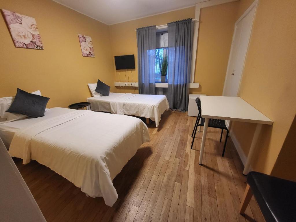 een kamer met 2 bedden, een tafel en een raam bij IzKaMaGe Hotel 2 in Västerås