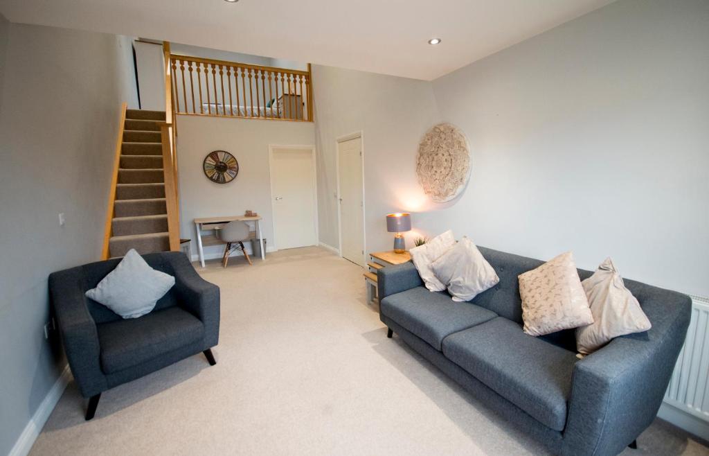 a living room with two blue couches and a staircase at Entire Duplex apartment for up to 6 guests, free wifi in Darlington
