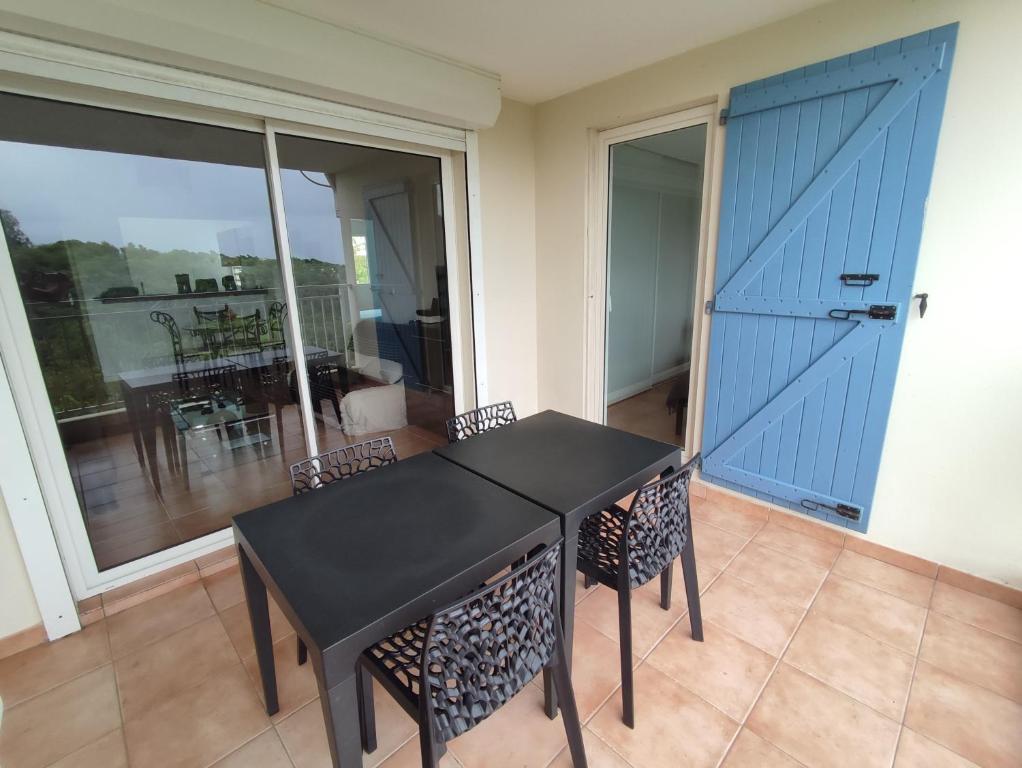 a black table and chairs in a room with a balcony at KAZADIDOU - Résidence Grand Cap - Vue Mer et Montagne - Piscine in Le Gosier