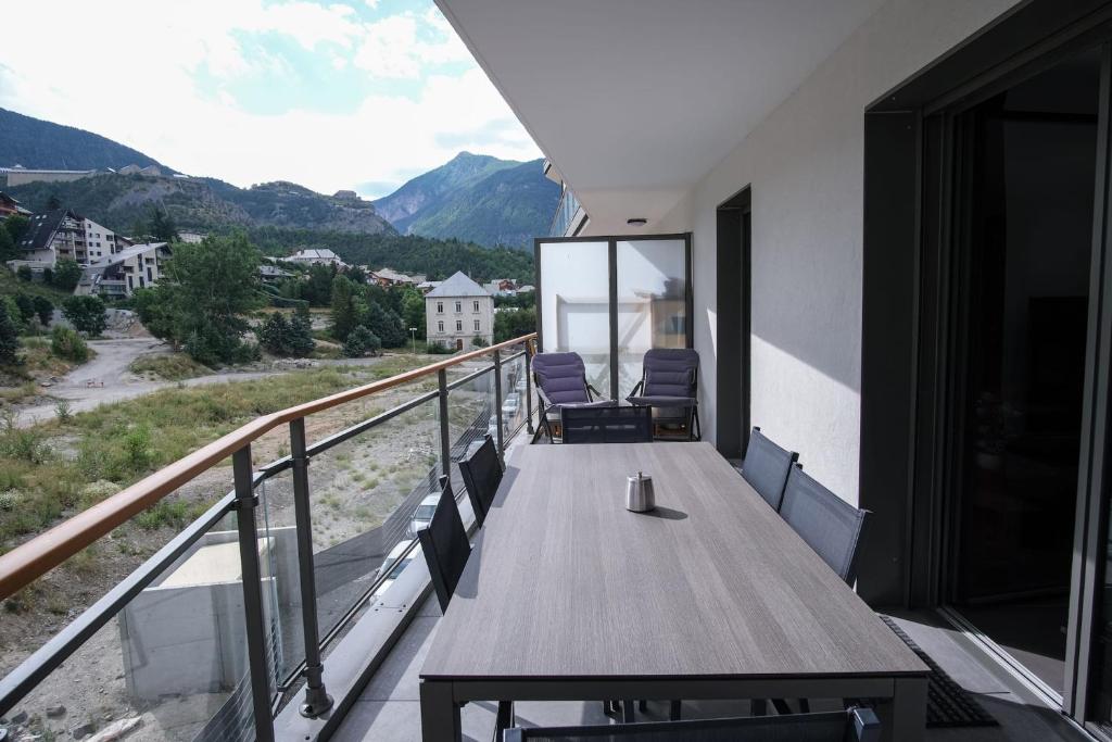 uma varanda de uma casa com uma mesa de madeira e cadeiras em SUPERB apt with BALCONY in BRIANÇON em Briançon