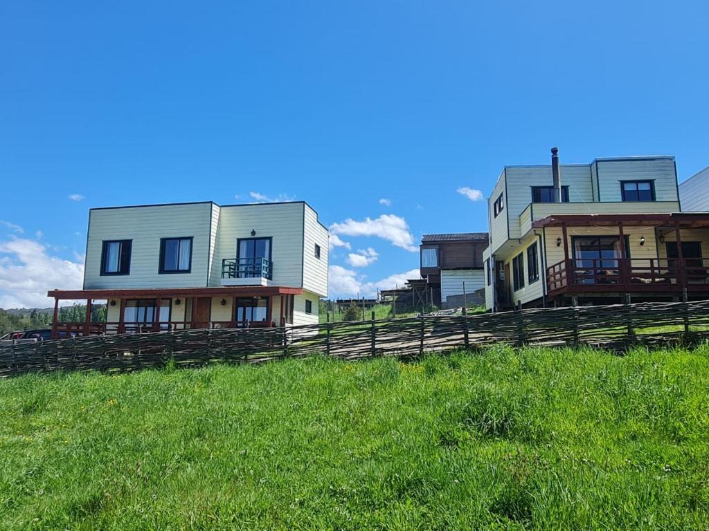 two houses sitting on top of a grassy hill at CASAS Y CABAÑAS CUMBRES DEL SOL in Castro